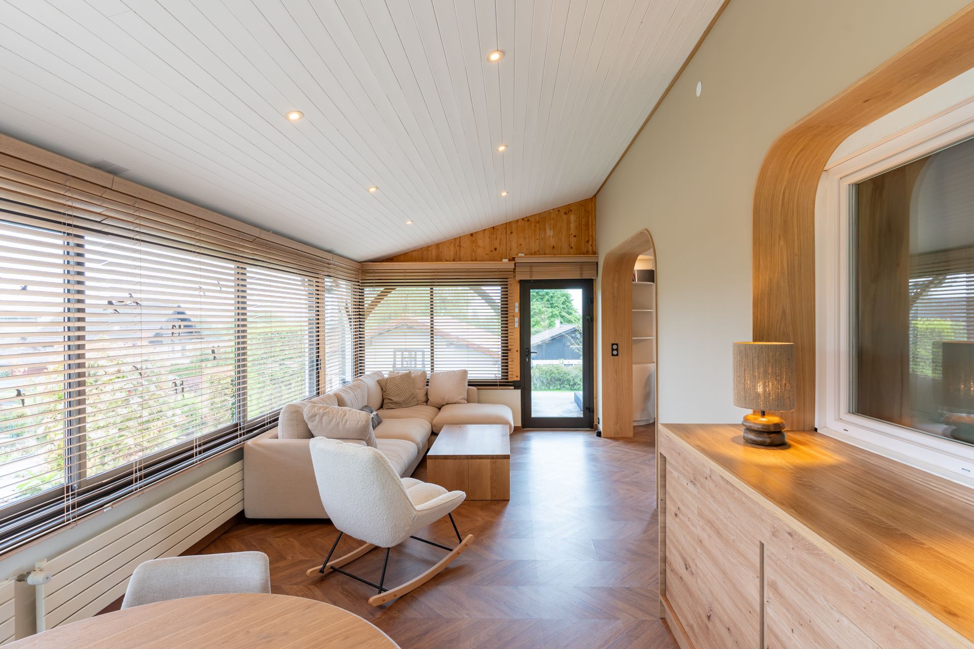 Salon moderne et chaleureux avec mobilier clair, bois naturel et grandes ouvertures sur l’extérieur