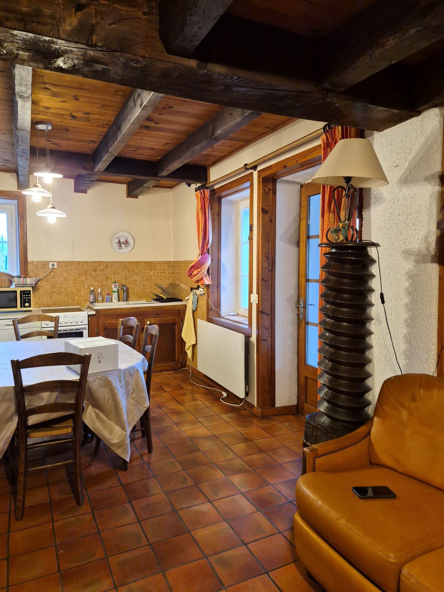 Cuisine avant rénovation avec ancien mobilier, cuisinière et revêtement mural d’origine